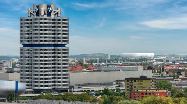 Der BMW-Turm (BMW-Vierzylinder oder BMW-Turm), im Hintergrund die Allianz Arena, Fußballstadion (Fußball Arena München, Schlauchboot) in München, Deutschland