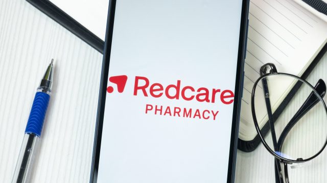 Redcare Pharmacy Logo auf einem Handy am Schreibtisch