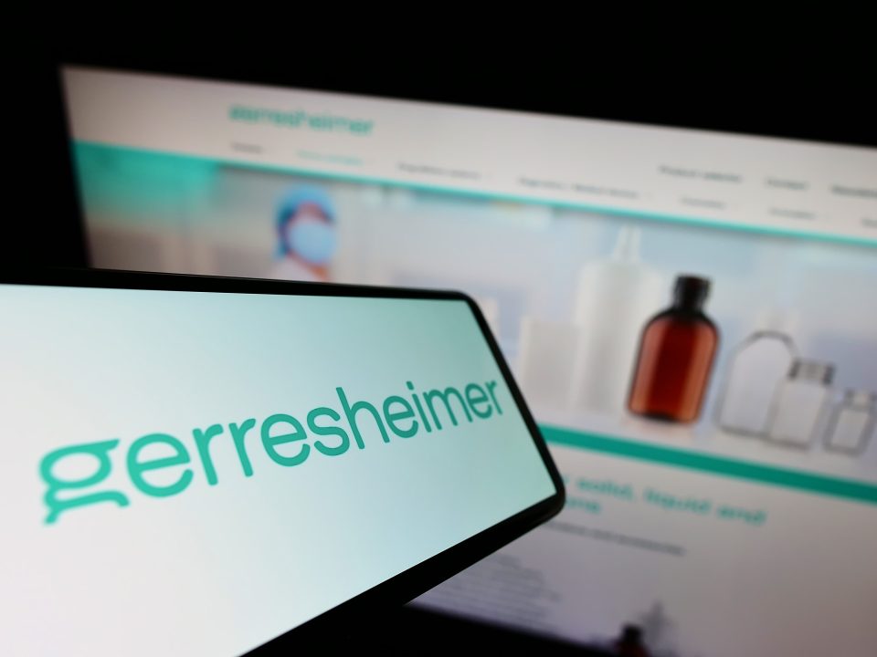 Mobiltelefon mit dem Logo des deutschen Verpackungsunternehmens Gerresheimer AG auf dem Bildschirm vor einer Unternehmenswebsite mit Fokus auf die rechte Mitte des Telefondisplay