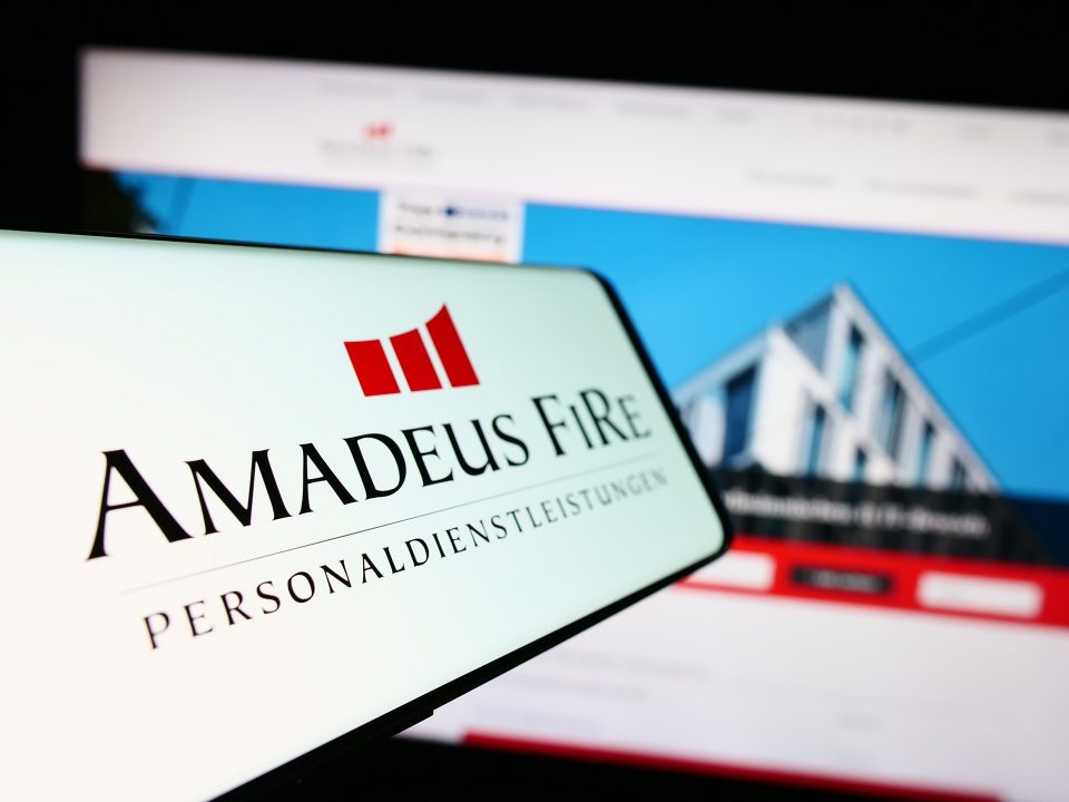 Ein Mobiltelefon mit dem Logo des deutschen Personaldienstleisters Amadeus FiRe AG auf dem Bildschirm vor einer Website mit Fokus auf der Mitte links des Telefondisplays