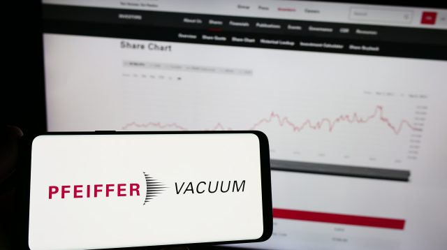 Eine Person hält ein Mobiltelefon mit dem Logo der deutschen Firma Pfeiffer Vacuum Technology AG auf dem Bildschirm vor einer Webseite mit Fokus auf das Telefondisplay