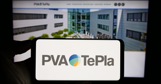 Eine Person hält ein Mobiltelefon mit dem Logo des deutschen Technologieunternehmens PVA TePla AG auf dem Bildschirm vor einer Geschäftswebseite mit Fokus auf das Telefondisplay