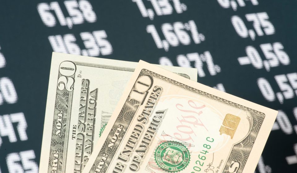 Dollar-Scheine und Kurse im Hintergrund