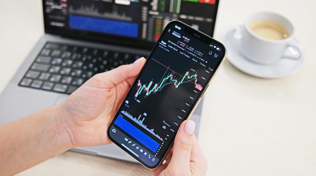 Mann analysiert Kurschart auf einem Handy