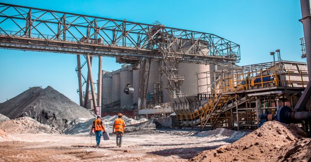 Moderne Zementproduktion: Industriemitarbeiter zwischen Anlagen, Sand- und Rohstoffhaufen