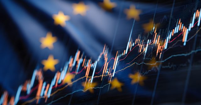 The European flag with yellow stars is blurred against the background of stock market charts,